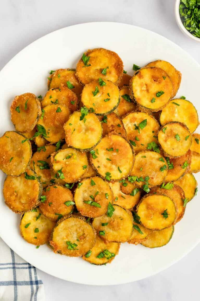 Fried zucchini garnished with parsley on a platter.