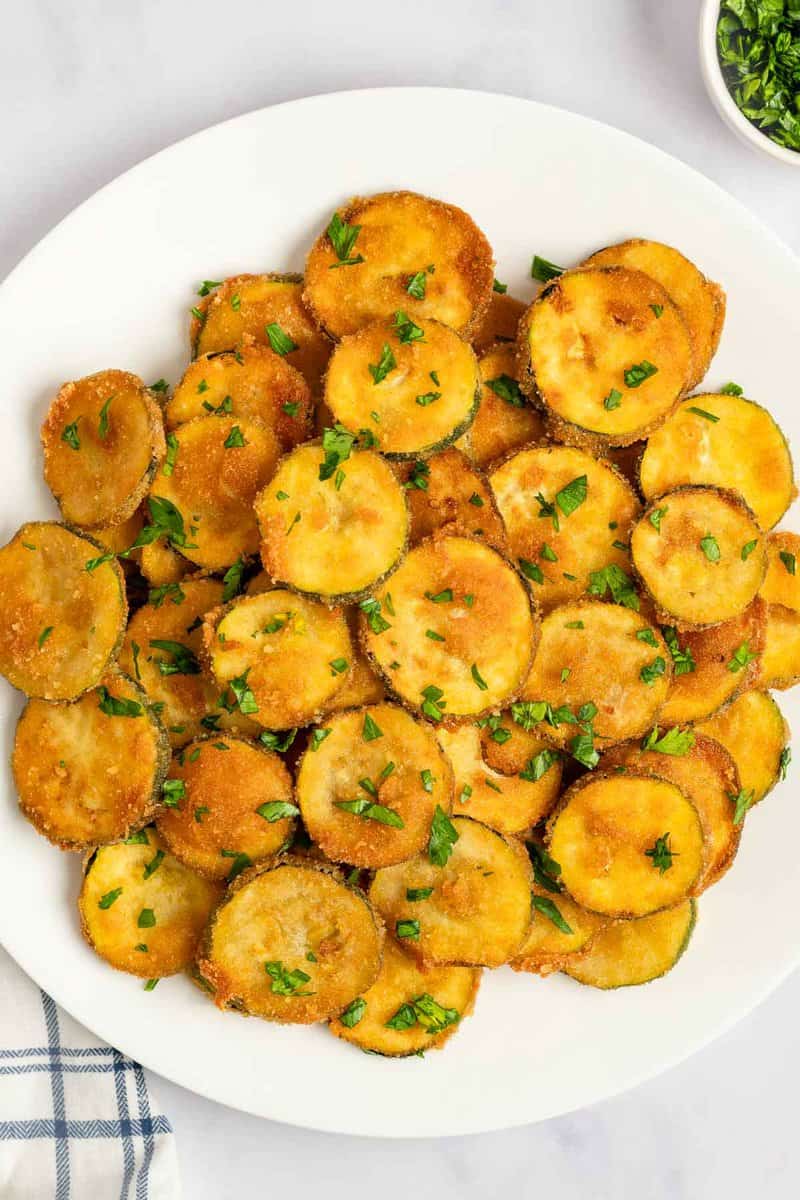 Fried zucchini garnished with parsley on a platter.