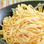 A bowl of pasta with egg, garlic, and parmesan cheese.