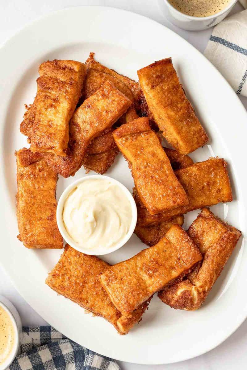 Copycat Pizza Hut Cinnamon Sticks and a bowl of cream cheese icing on a platter.