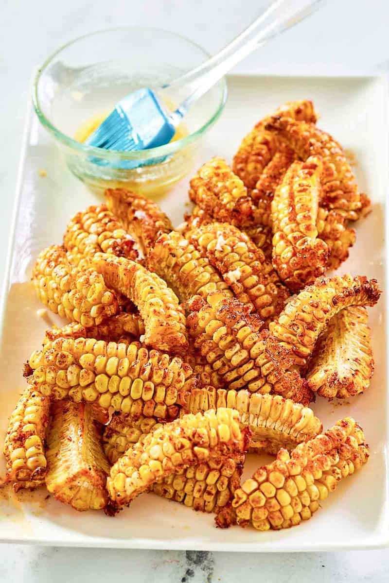 Air fryer corn ribs and a bowl of garlic butter on a platter.