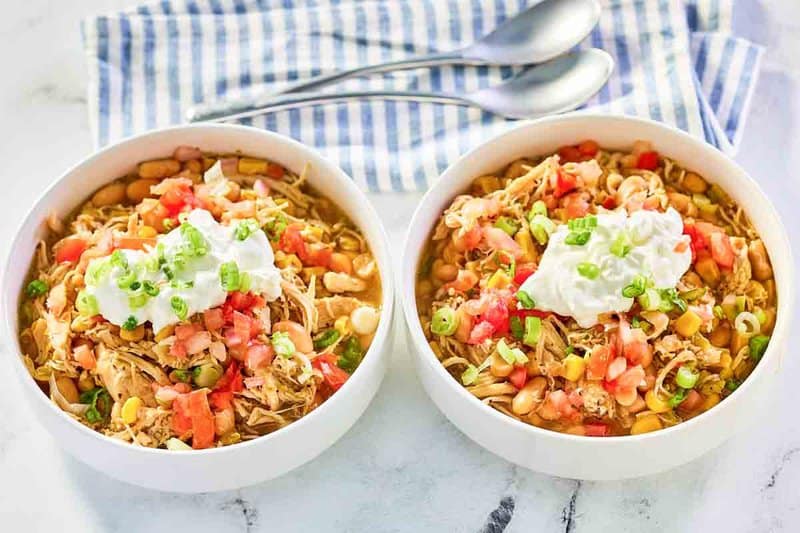 Two bowls of crockpot white chicken chili with beans.