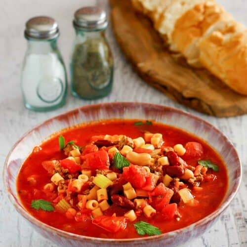 Copycat Olive Garden pasta e fagioli, bread slices, salt, and pepper.