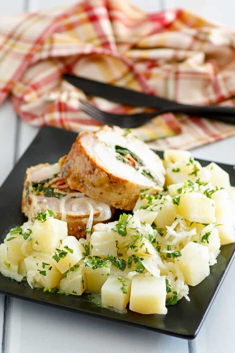 Buttery parsley potatoes and stuffed pork loin slices on a plate.