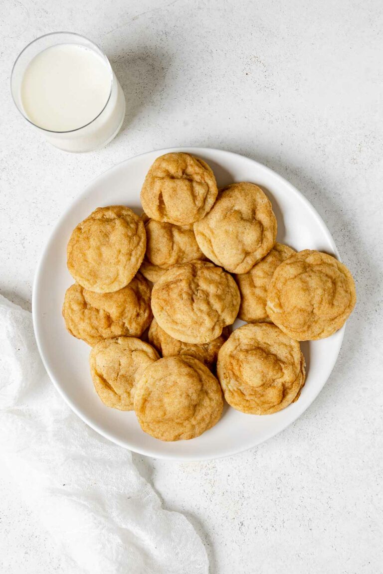A plate of homemade snickerdoodle cookies and a glass of milk beside it.