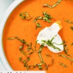 Homemade La Madeleine red pepper soup garnished with fresh basil.