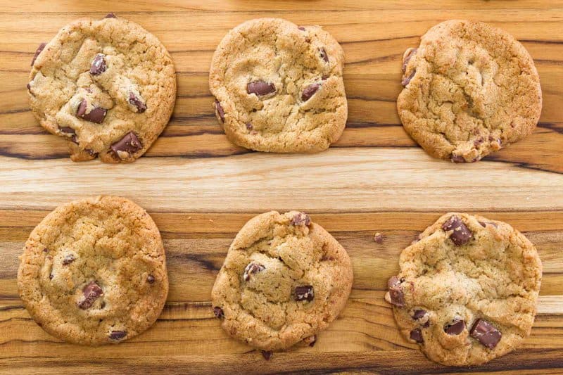 Six chocolate chippers on a wood board.