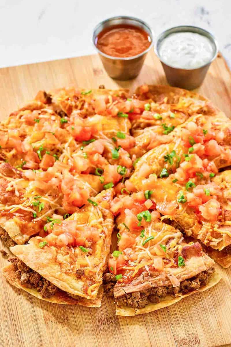 Copycat Taco Bell Mexican pizza and cups of taco sauce and sour cream.