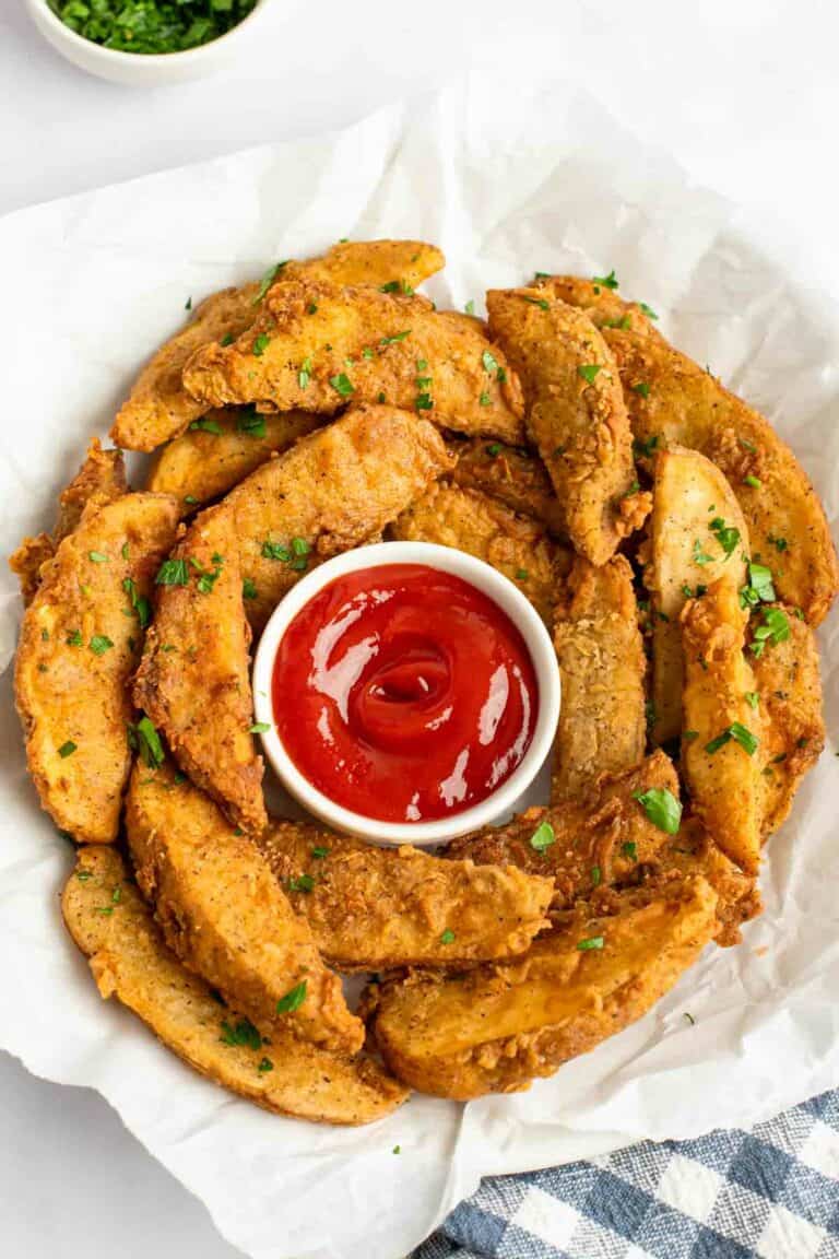Copycat KFC potato wedges and ketchup in a serving bowl lined with parchment.