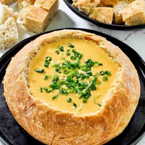 Copycat Red Lobster ultimate fondue in a bread bowl and bread cubes beside it.