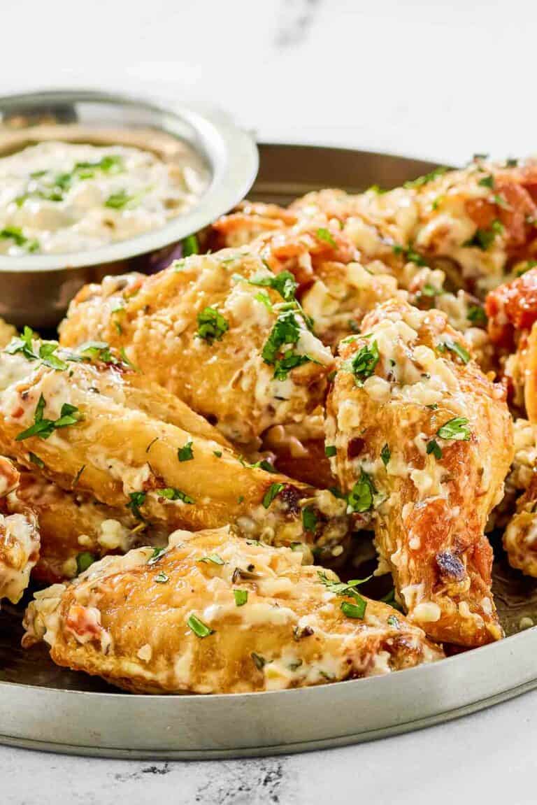 Copycat Buffalo Wild Wings garlic parmesan wings and sauce on a plate.