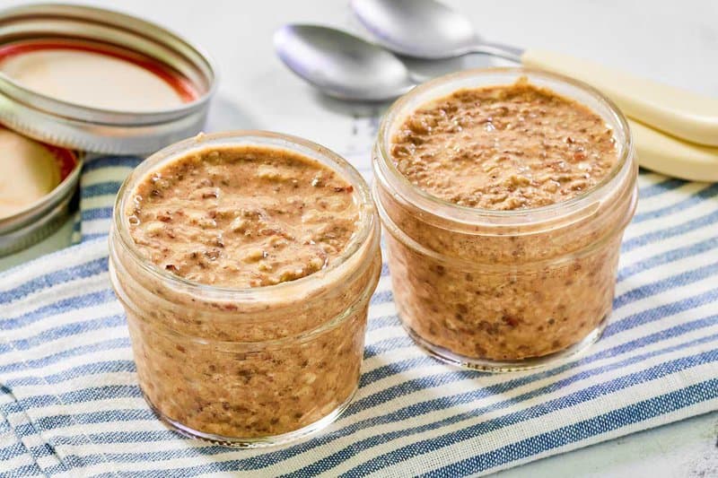 Two homemade brekki overnight oats on a cloth napkin and two spoons.