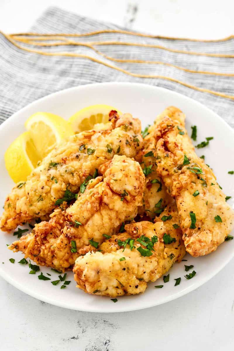 Copycat Piada chicken tenders and lemon wedges on a plate.