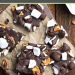 Homemade rocky road candy with walnuts scattered on a wood board.