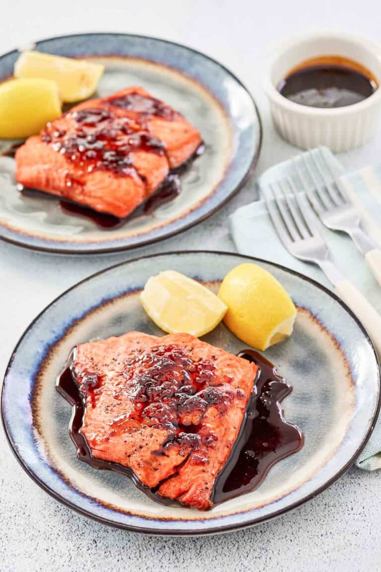 Copycat Cheddar's bourbon glazed salmon and lemon wedges on two plates.