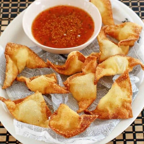Cream cheese wontons and a small bowl of dipping sauce.