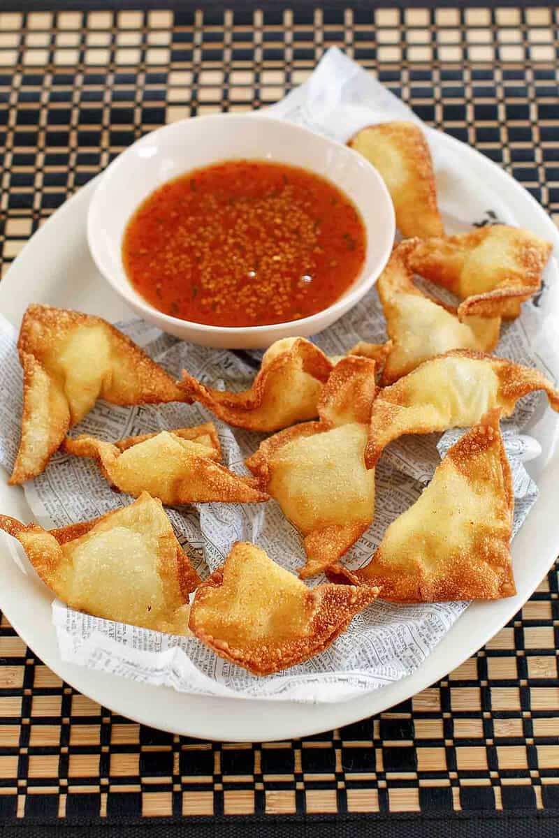 Cream cheese wontons and a small bowl of dipping sauce.