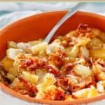Crockpot cheesy potatoes and a spoon in a small bowl.