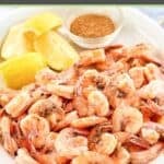 Boiled shrimp, lemon wedges, and a small cup of seafood seasoning.