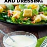 A small bowl of homemade Commander's Palace salad dressing and a salad behind it.