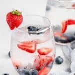 A glass of berry infused water with fresh berries in it.