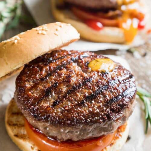 Grilled backyard burger with tomato on a sesame seed bun.
