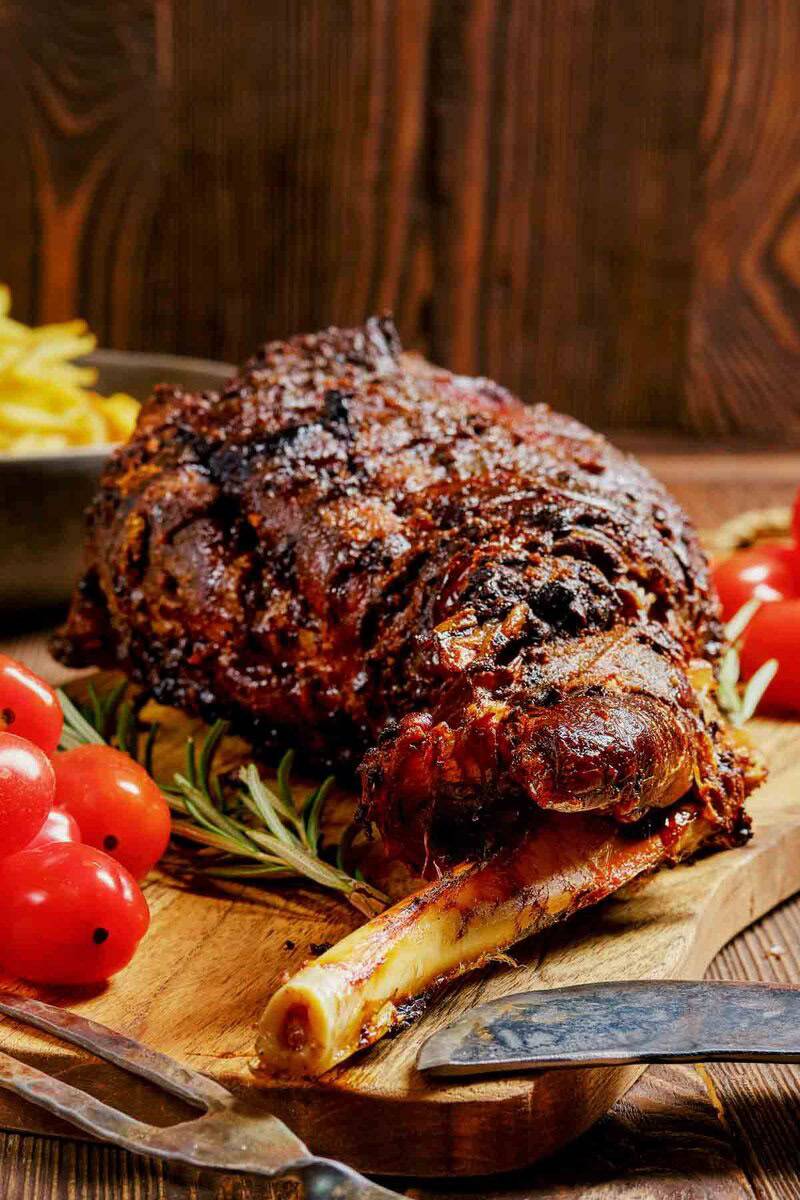 Oven roasted Indian style kashmiri leg of lamb on a cutting board.