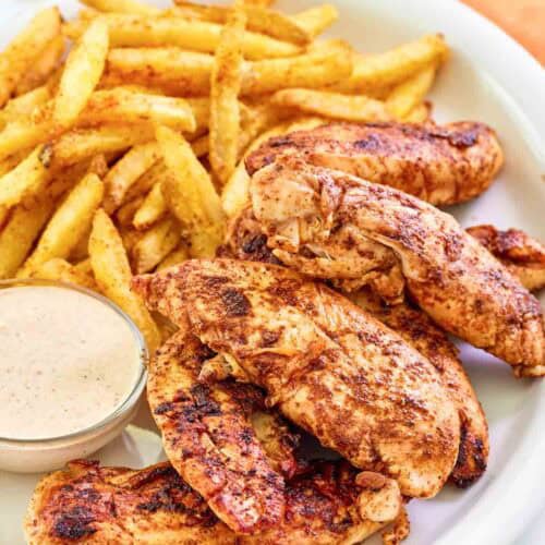 Copycat Popeyes blackened chicken tenders served with fries and dipping sauce.