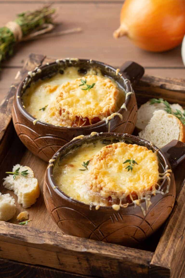 Bowls of homemade classic French onion soup on a wood tray.