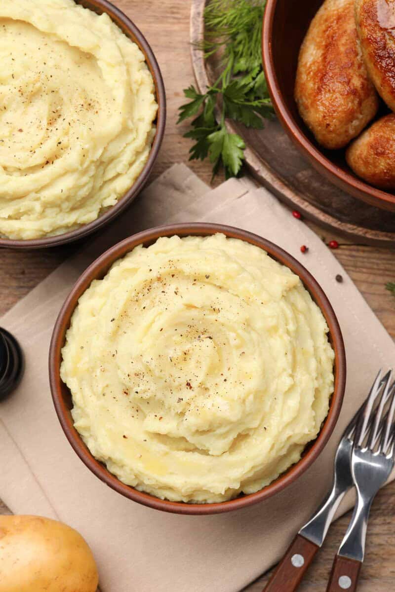 two bowls of fluffy mashed potatoes seasoned with pepper