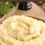 A bowl of homemade mashed potatoes with black pepper sprinkled on top.