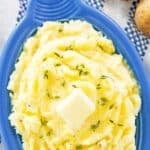 Yukon gold mashed potatoes topped with butter in a serving dish.
