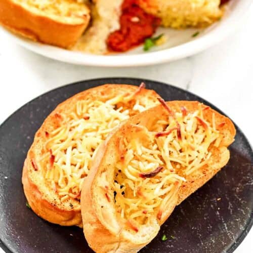Slices of copycat Marie Callender's garlic toast on a plate and with lasagna.