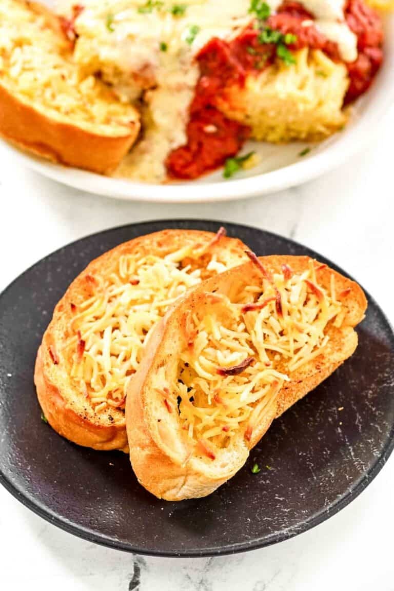 Slices of copycat Marie Callender's garlic toast on a plate and with lasagna.