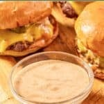 Homemade sonic smasher sauce in a small bowl and burgers on a wood board.