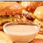 Homemade Sonic smasher sauce in a small glass bowl and burgers behind it.