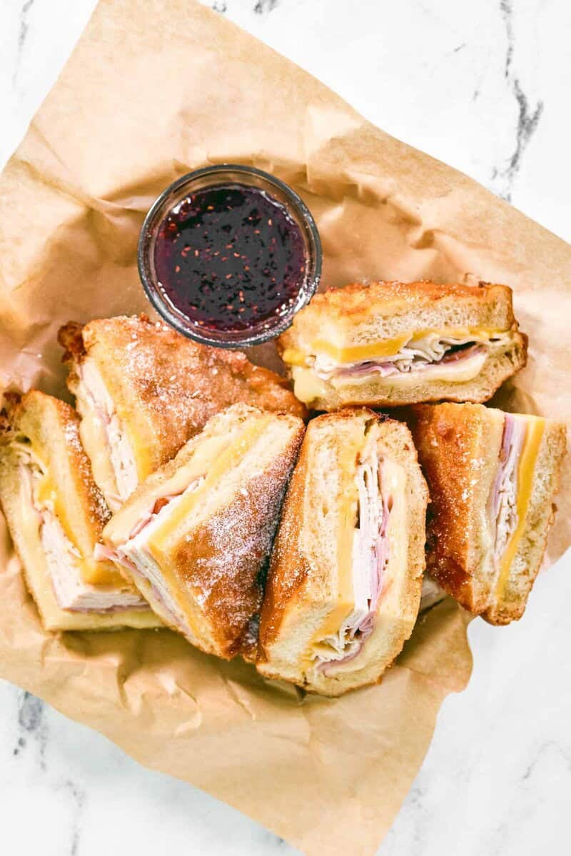 Copycat Cheddar's monte cristo sandwich and a small cup of raspberry jam in a serving basket.