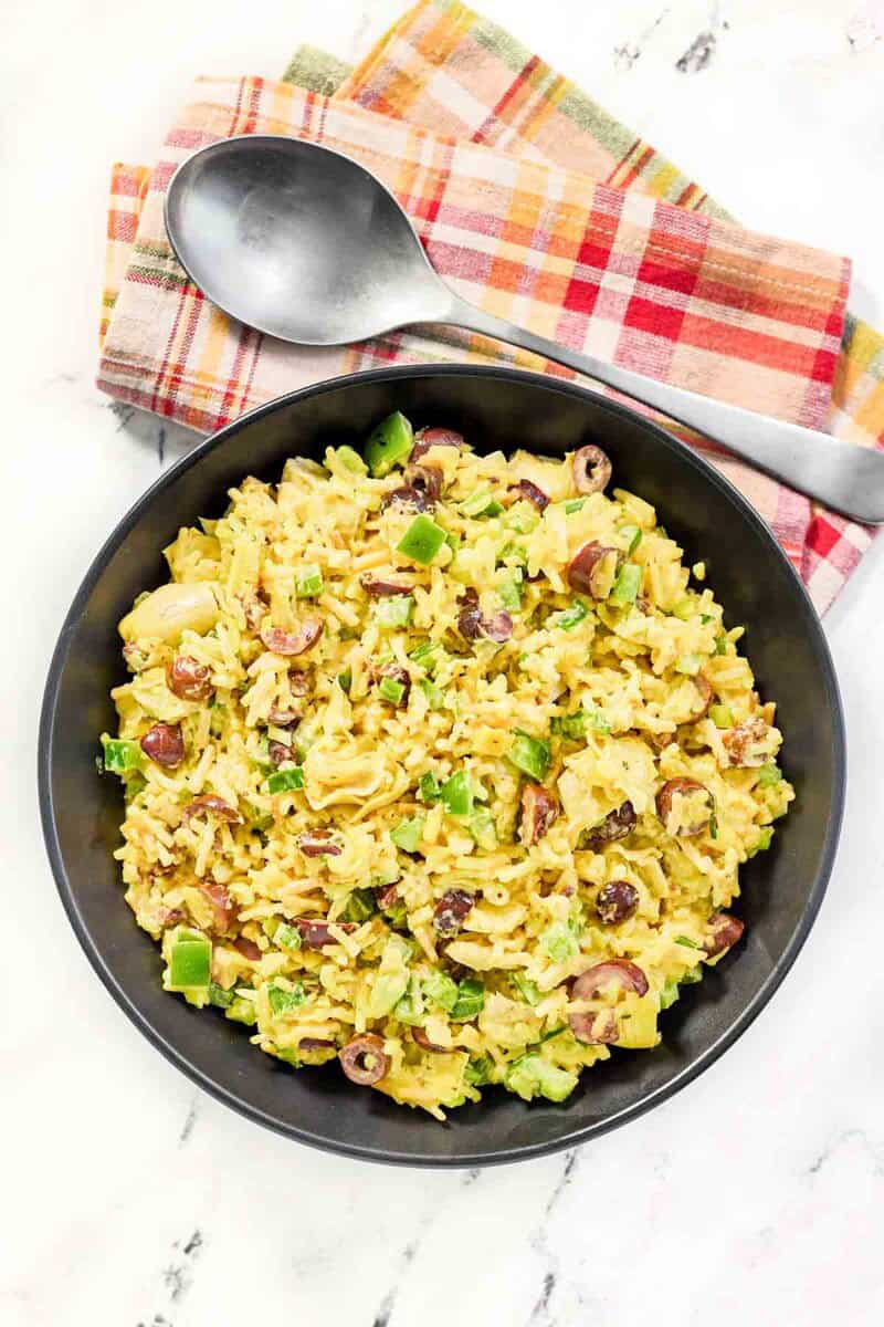 Rice-A-Roni artichoke salad with curry in a large bowl and a serving spoon next to it.