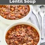 Homemade Carrabba's sausage lentil soup in two bowls and two spoons on a cloth napkin.