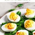 Classic deviled eggs and spinach leaves on a platter.