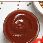 A bowl of homemade Swiss Chalet BBQ sauce, peppercorns, and tomatoes.