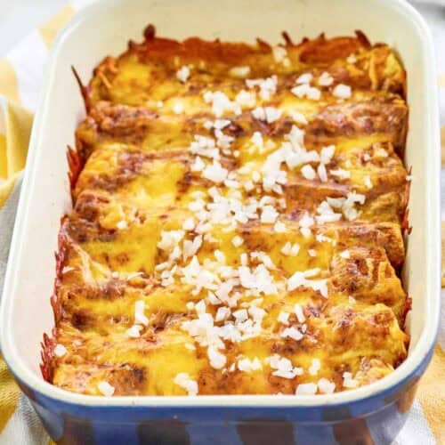 Copycat El Chico cheese enchiladas in a baking dish and a spatula behind it.