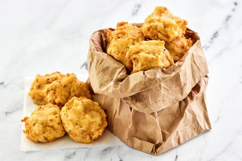 Copycat Fat Ronnie's deep fried mushrooms in and beside a small paper bag.