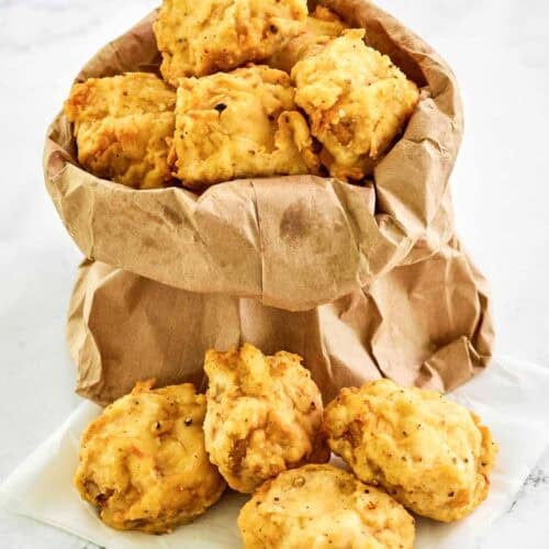 Copycat Fat Ronnie's deep fried mushrooms in a small paper bag and on parchment paper.