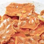 Pieces of homemade almond brittle candy piled on a large plate.