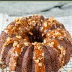 Triple chocolate bundt cake topped with chocolate sauce, chocolate chips, and pecans.