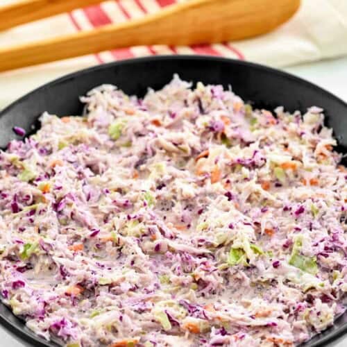A bowl of copycat Famous Dave's coleslaw and wooden serving tongs behind it.