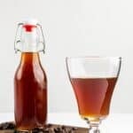 Homemade Kahlua coffee liqueur in a shot glass and bottle.