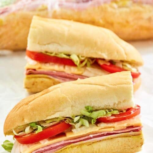 Copycat Kmart sub sandwich cut in half and another behind it wrapped in plastic.