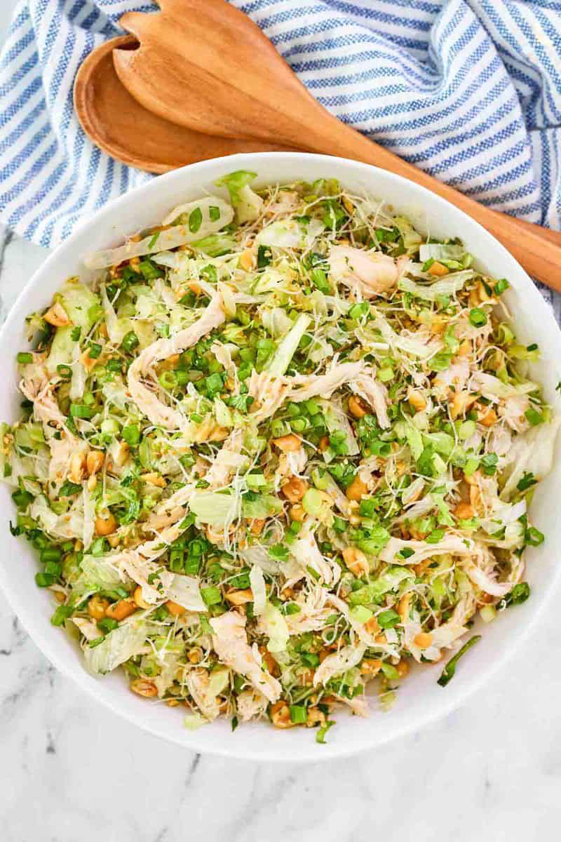 Copycat Ming's Thai chicken salad and wooden salad servers on a cloth napkin.
